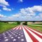 Country road with American flag, blue sky with white clouds.