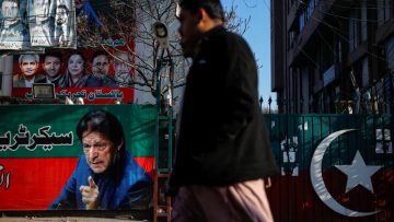 People walk past a banner with a picture of the former Prime Minister Imran Khan outside the party office of Pakistan Tehreek-e-Insaf (PTI), a day after the general election, in Lahore